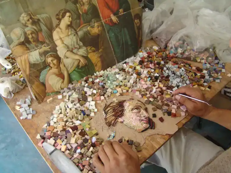 Working at the table making mosaic artwork with smalti glass