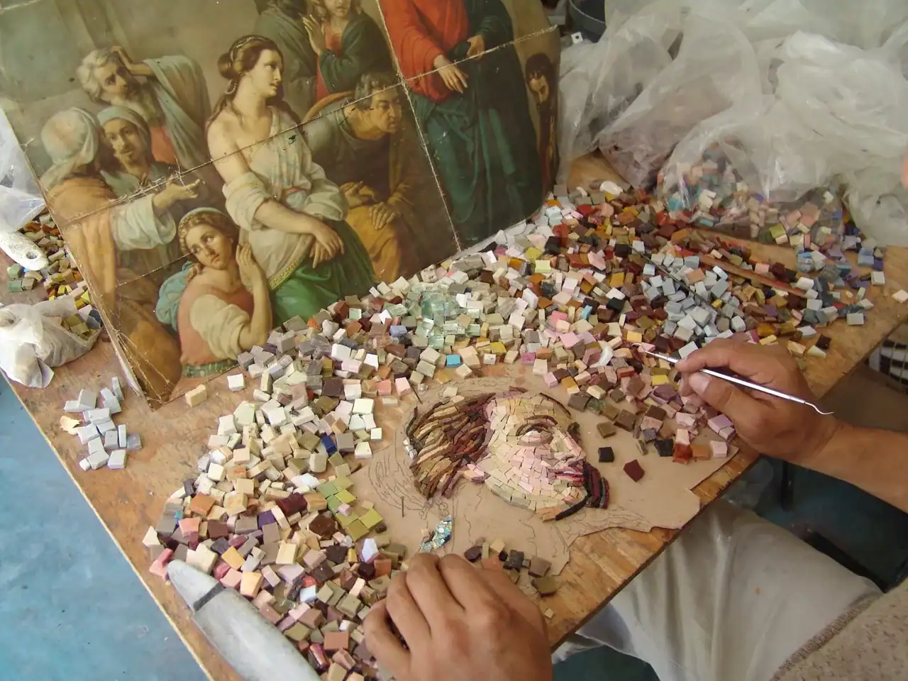 Working at the table making mosaic artwork with smalti glass