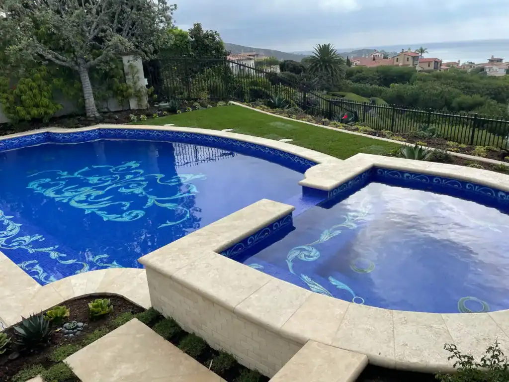 Custom mosaic pool with intricate blue patterns in a luxurious outdoor setting.