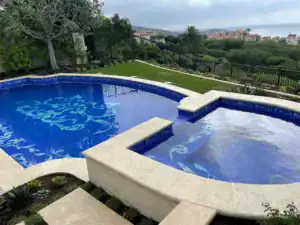 Custom mosaic pool with intricate blue patterns in a luxurious outdoor setting.